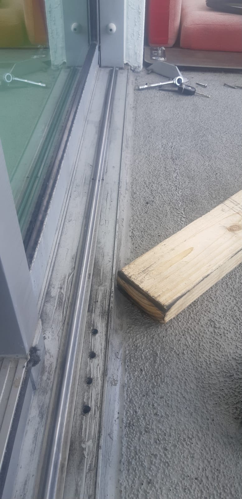 Wire brush cleaning of corroded aluminum sliding door track during professional track restoration service