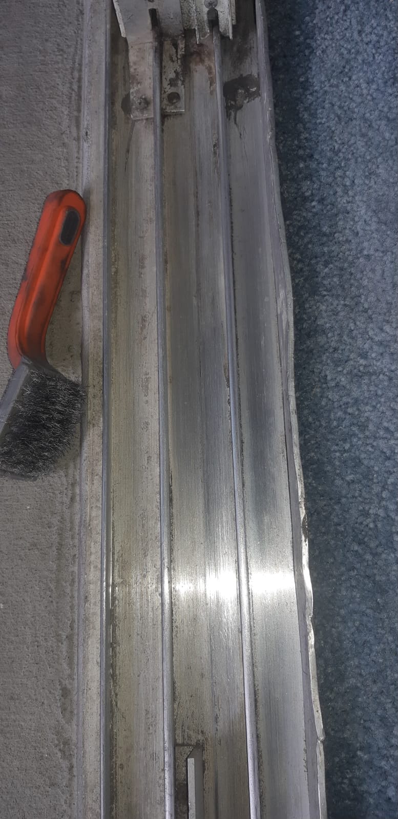 Seized steel roller cartridge extracted from sliding door bottom rail — axle corroded from South Florida salt exposure