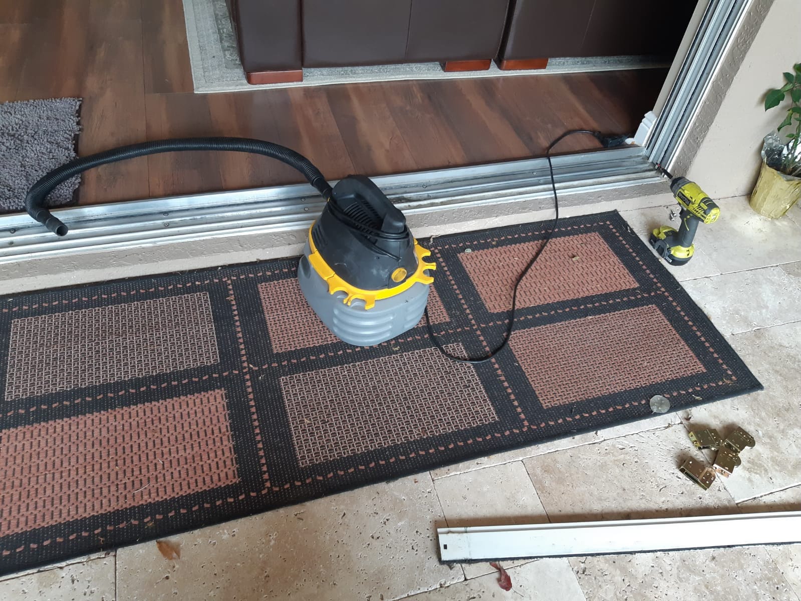 Sliding door track replacement in progress — new extruded aluminum track section laid next to frame, drill and wet/dry vac on site