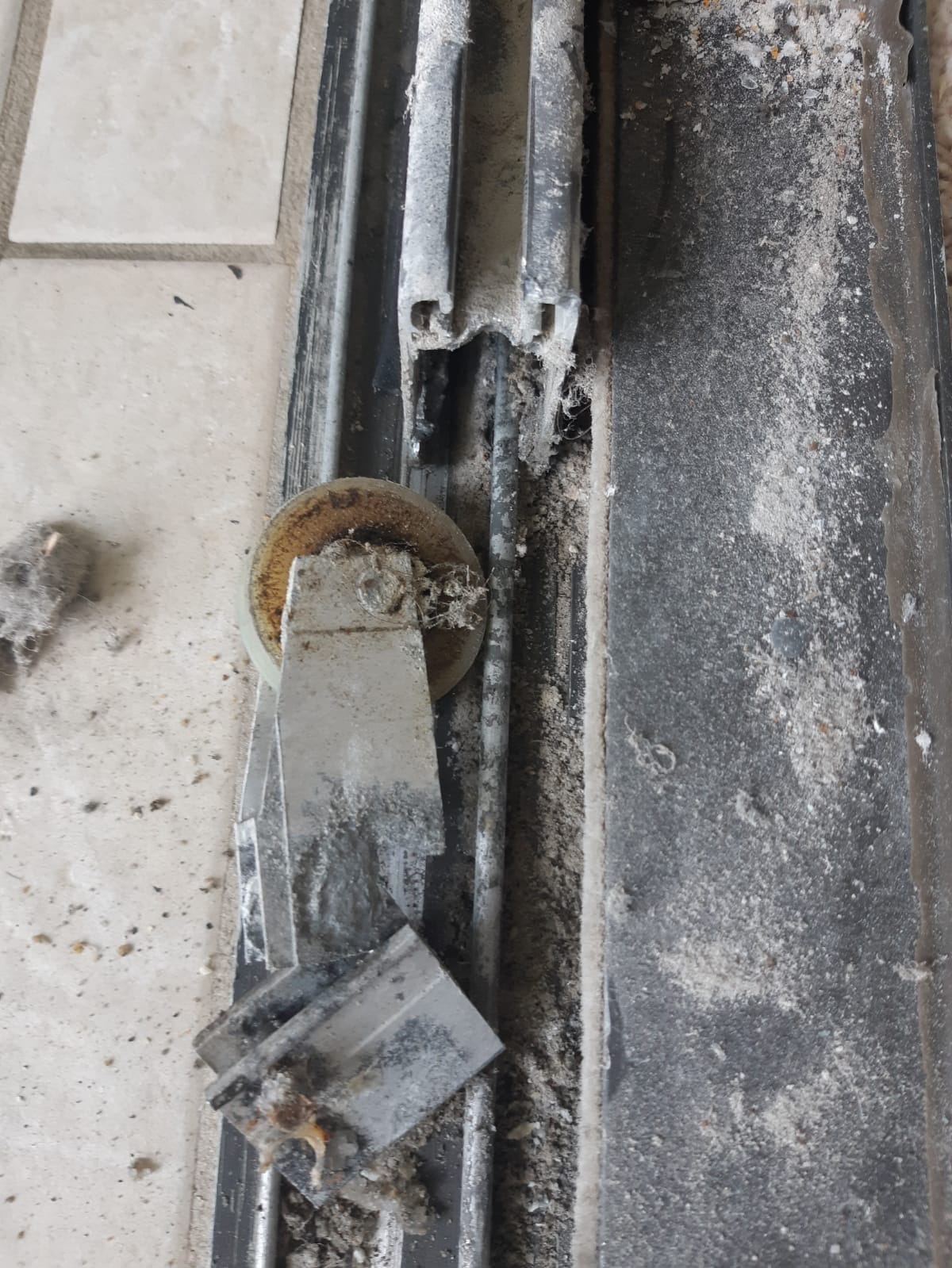 Corroded, grime-packed roller body removed from sliding door frame during track-and-roller service, South Florida