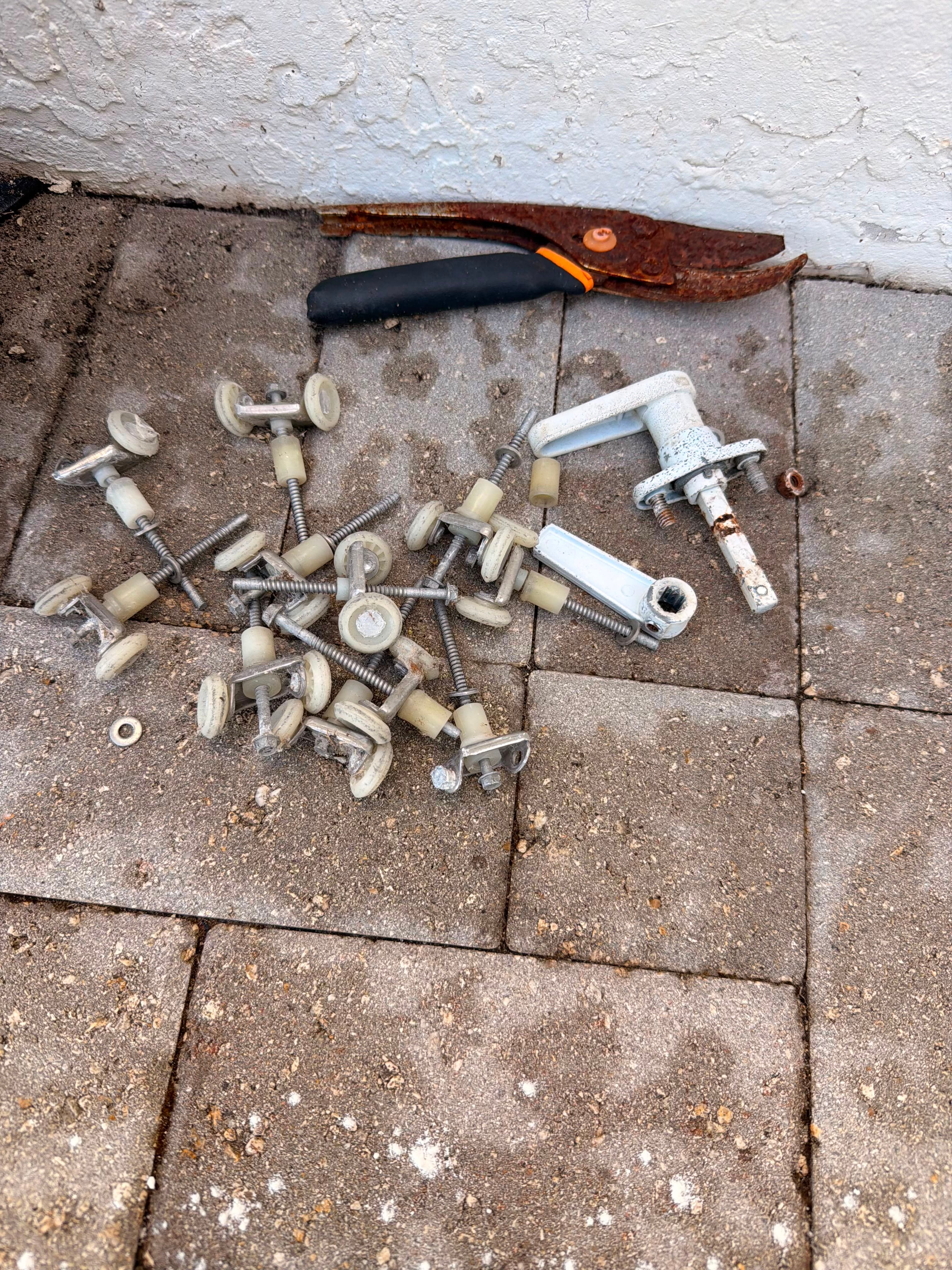Accordion shutter wheel carriers, brackets and corroded lock hardware removed during repair