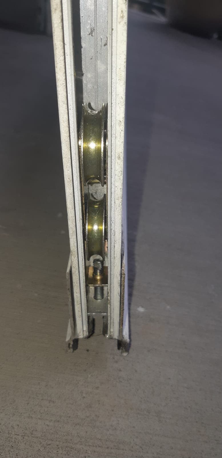 Tandem roller with two wheels and an adjustment screw seated in the end of a sliding door bottom rail